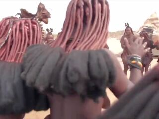 Afrikansk himba kvinnor dansa och gunga deras saggy tuttarna runt